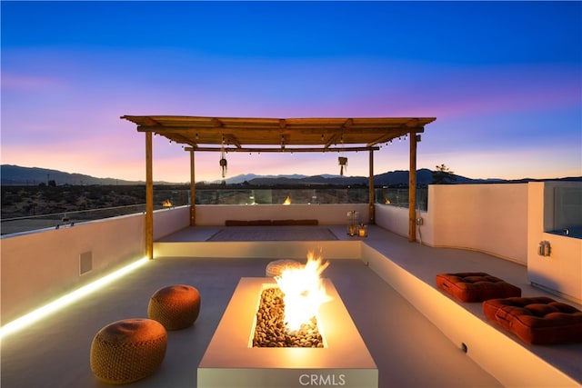 patio terrace at dusk with a mountain view, a pergola, and an outdoor fire pit