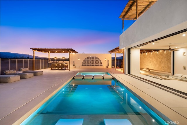 pool at dusk with a patio area and outdoor lounge area