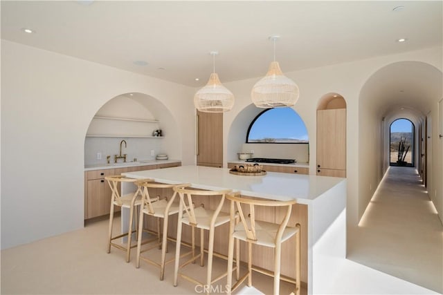 kitchen featuring a kitchen breakfast bar, a kitchen island, hanging light fixtures, and sink