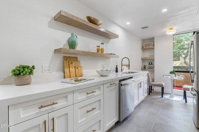 kitchen featuring sink, light stone countertops, light tile patterned floors, white cabinetry, and stainless steel appliances