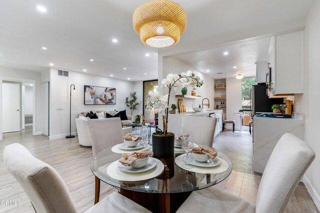 dining space featuring light wood-type flooring and sink