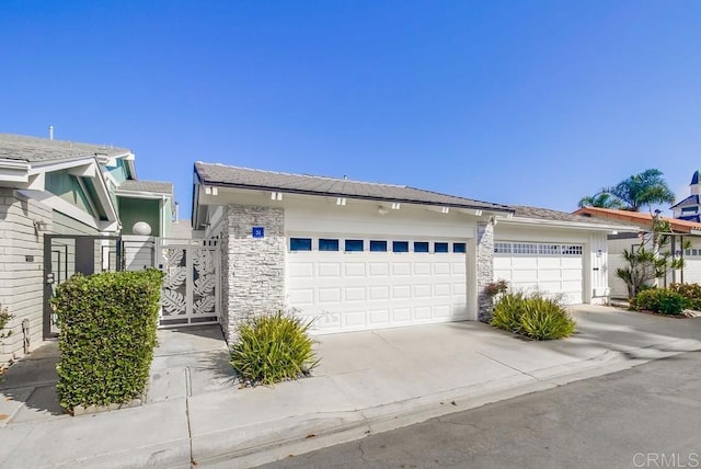51 Catspaw, Coronado, CA 92118 - view of front of home with stone siding, a gate, a garage, and concrete driveway
