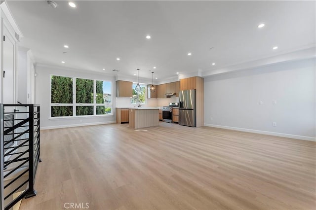 kitchen with pendant lighting, crown molding, light wood-type flooring, appliances with stainless steel finishes, and a kitchen island