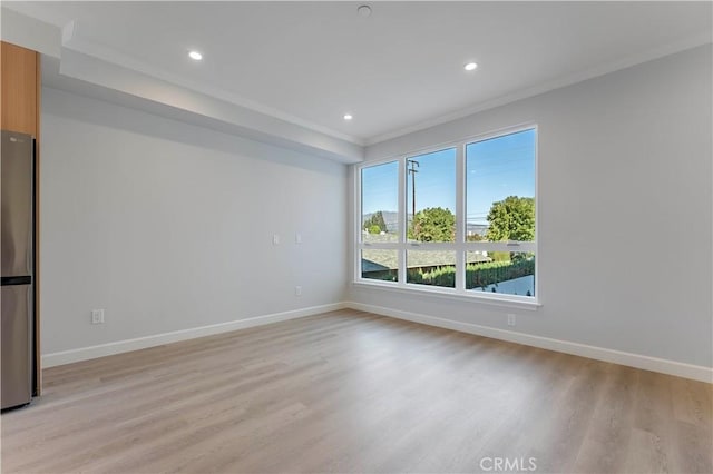 unfurnished room featuring ornamental molding and light wood-type flooring