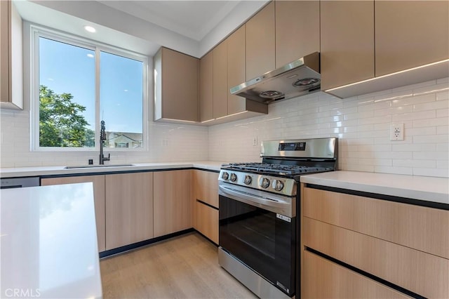 kitchen featuring backsplash, sink, stainless steel gas range, range hood, and light hardwood / wood-style floors