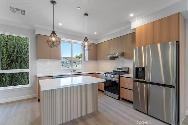 kitchen featuring appliances with stainless steel finishes, tasteful backsplash, sink, pendant lighting, and light hardwood / wood-style floors