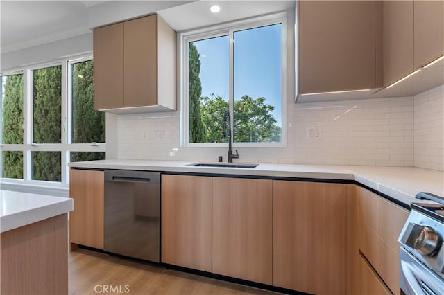 kitchen with light brown cabinets, backsplash, sink, appliances with stainless steel finishes, and light hardwood / wood-style floors