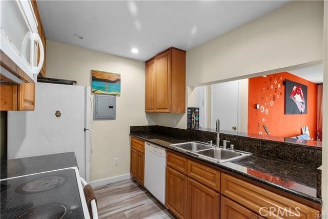 kitchen featuring light hardwood / wood-style flooring, dark stone counters, sink, electric panel, and white appliances