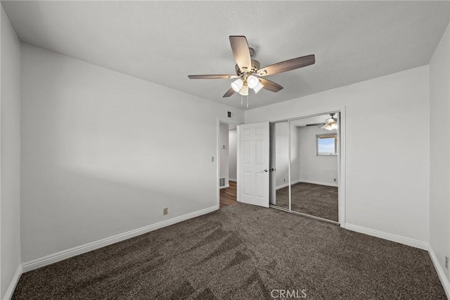 unfurnished bedroom featuring ceiling fan, a closet, and dark colored carpet