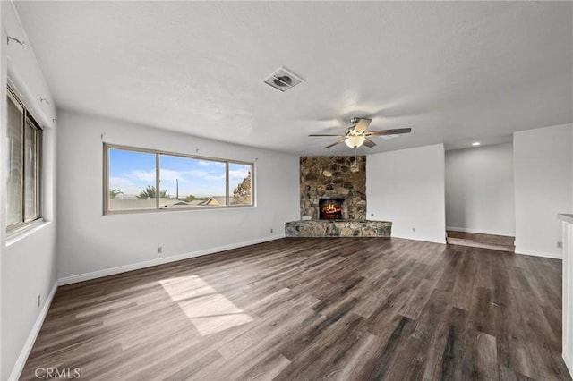 unfurnished living room featuring ceiling fan, a stone fireplace, and wood-type flooring