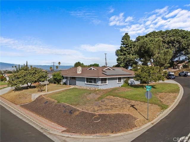 single story home featuring a front yard and solar panels