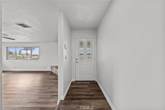 doorway with a textured ceiling, ceiling fan, and dark hardwood / wood-style floors