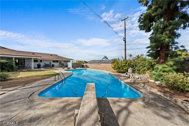 view of swimming pool with a patio and a diving board