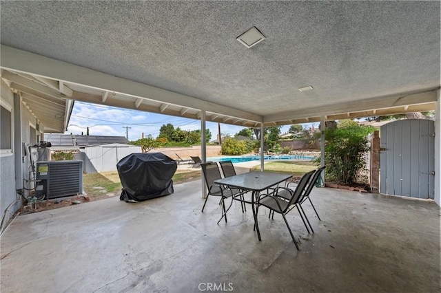 view of patio / terrace with a storage unit, a fenced in pool, central AC unit, and a grill