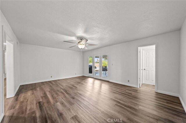 spare room featuring a textured ceiling, ceiling fan, and dark wood-type flooring