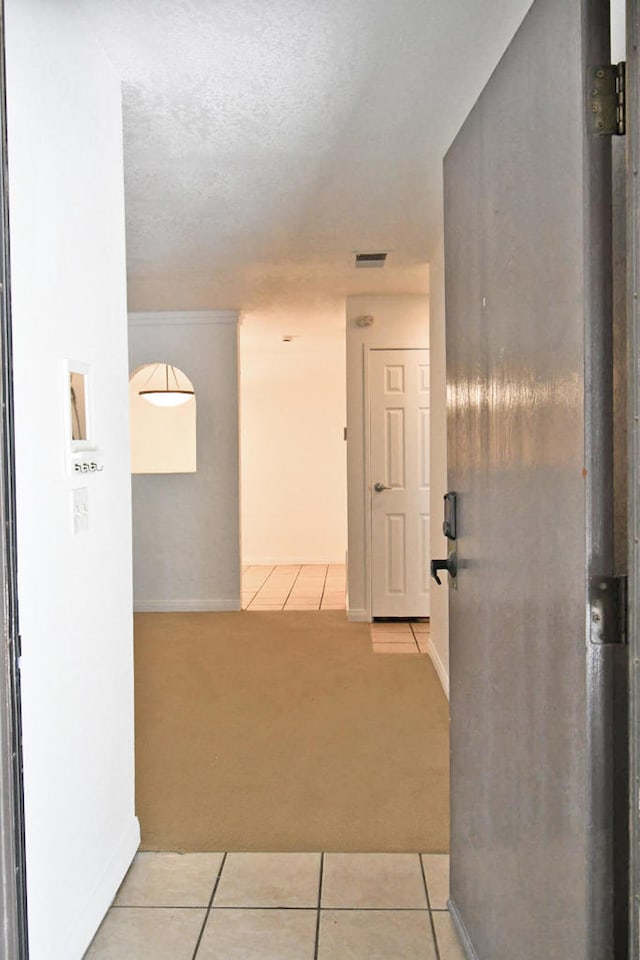 corridor with light carpet and a textured ceiling