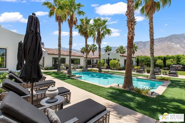 view of pool with a patio area, a mountain view, and a yard