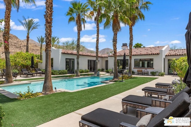 back of property with a patio area, a mountain view, and a yard