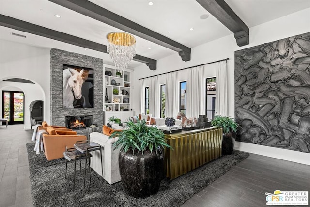 living room featuring an inviting chandelier, a healthy amount of sunlight, wood-type flooring, and a stone fireplace