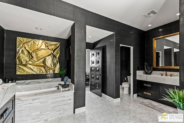 bathroom with tiled bath, toilet, vanity, and tile patterned flooring