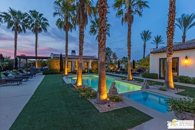 pool at dusk featuring a lawn and a pergola