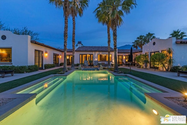 pool at dusk featuring a lawn