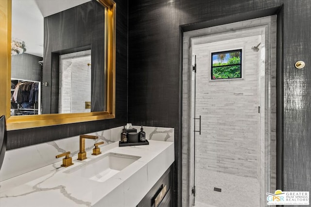 bathroom featuring a shower with shower door and vanity