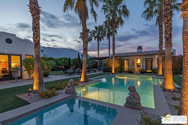 pool at dusk featuring a patio area and a mountain view