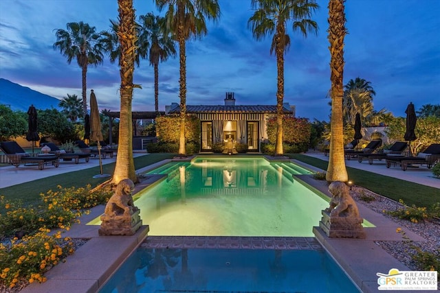 pool at dusk featuring an outbuilding and a patio area