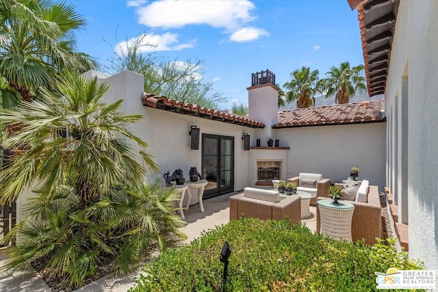 back of property featuring a patio area and an outdoor living space with a fireplace