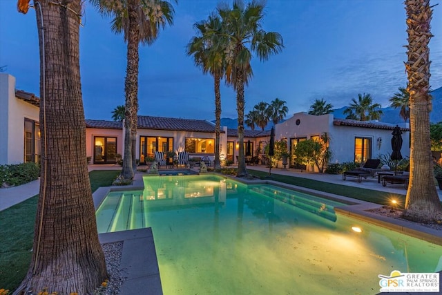 pool at dusk with a patio area