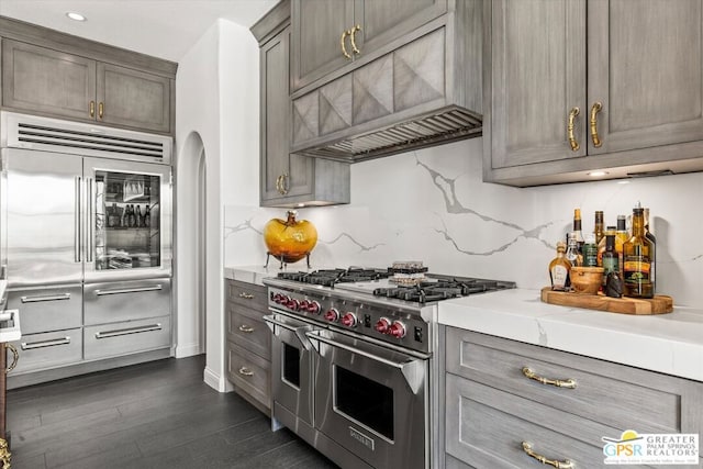 kitchen with custom exhaust hood, backsplash, dark hardwood / wood-style flooring, and high end appliances