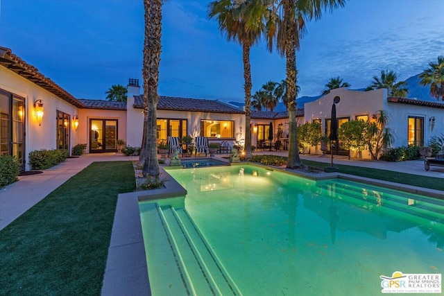 pool at dusk with a yard and a patio