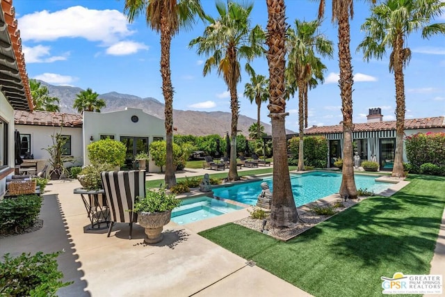 view of pool featuring a mountain view, a patio area, an in ground hot tub, and a lawn