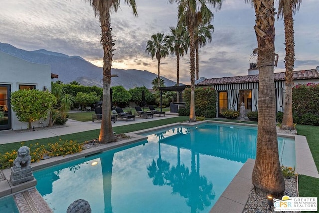 pool at dusk with a patio area and a mountain view