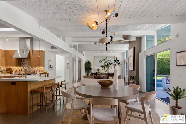 dining space with concrete flooring, sink, and beamed ceiling