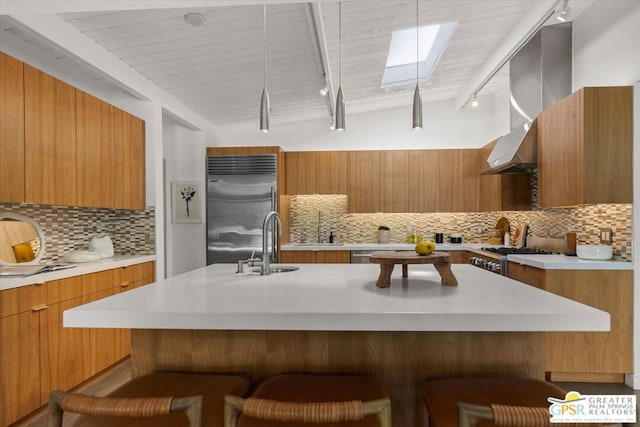 kitchen with built in refrigerator, decorative backsplash, a kitchen breakfast bar, lofted ceiling with skylight, and sink