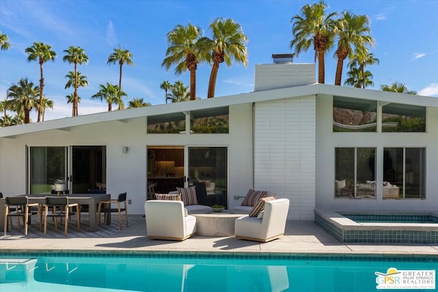 rear view of house featuring a patio area and a pool with hot tub