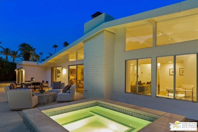 back of house with a patio and an in ground hot tub