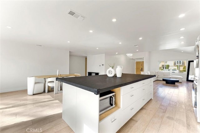 kitchen with a center island, light hardwood / wood-style flooring, and white cabinets