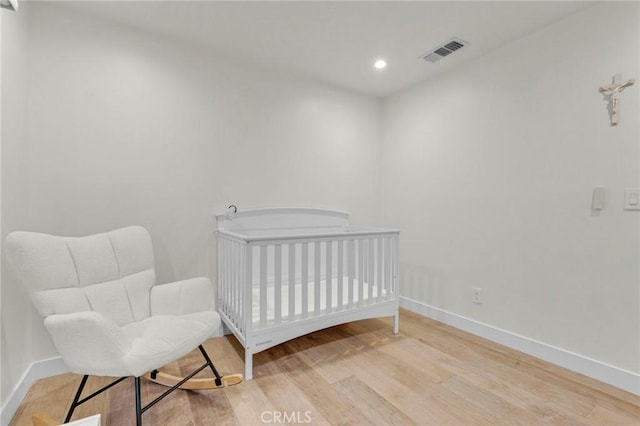 bedroom featuring a crib and light hardwood / wood-style flooring