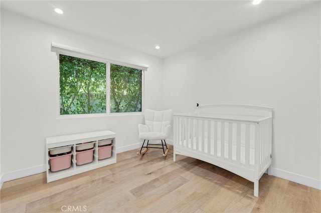 bedroom featuring a crib and light hardwood / wood-style floors