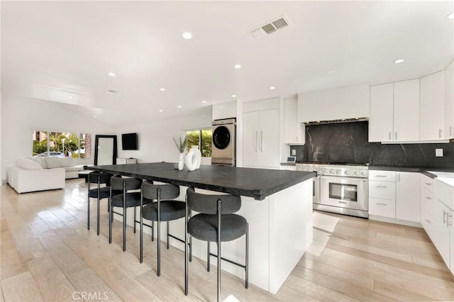 kitchen with a breakfast bar area, stacked washer / dryer, a center island, and light wood-type flooring