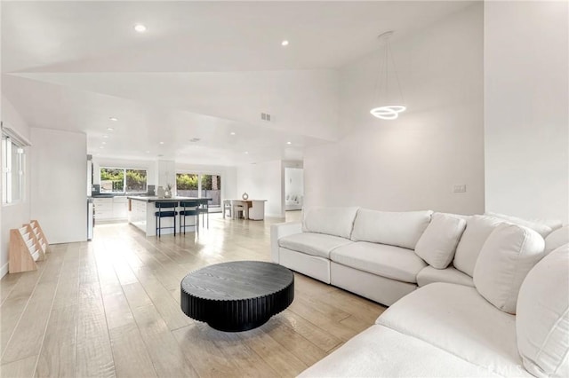 living room with high vaulted ceiling and light wood-type flooring