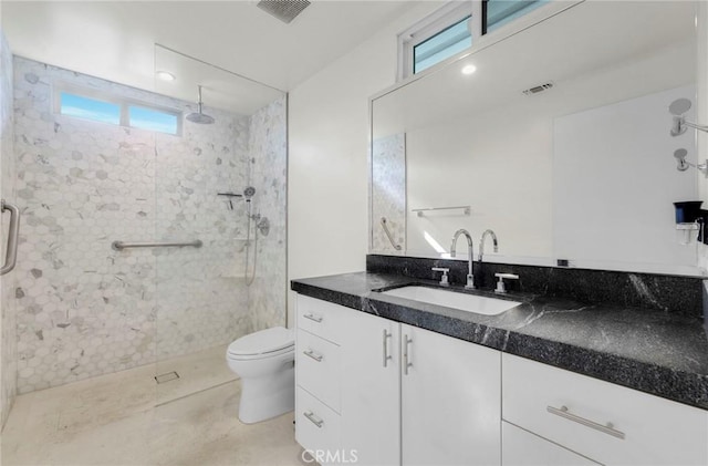 bathroom featuring tile patterned flooring, vanity, a healthy amount of sunlight, and a tile shower