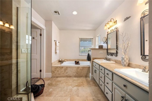 bathroom featuring a bath, double vanity, a sink, and visible vents