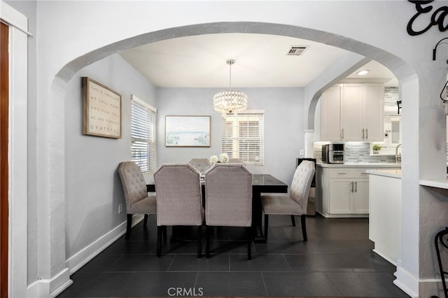 tiled dining room with a chandelier