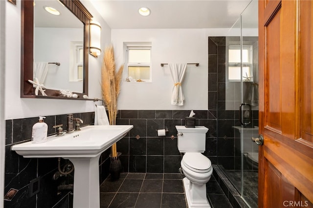 bathroom with toilet, tile patterned floors, an enclosed shower, and tile walls