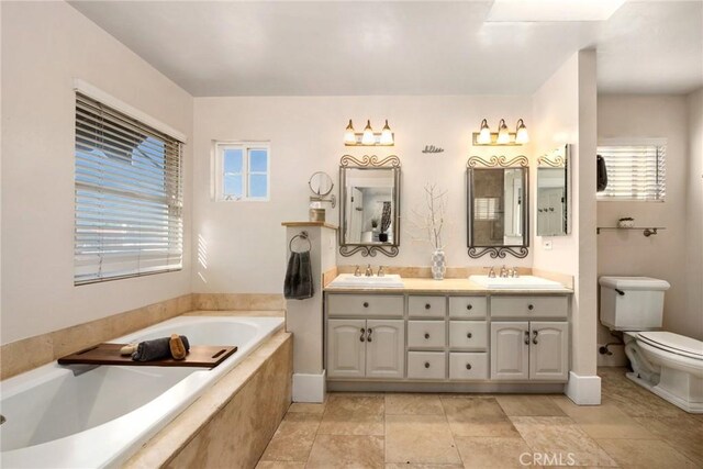 bathroom featuring vanity, tiled bath, plenty of natural light, and toilet