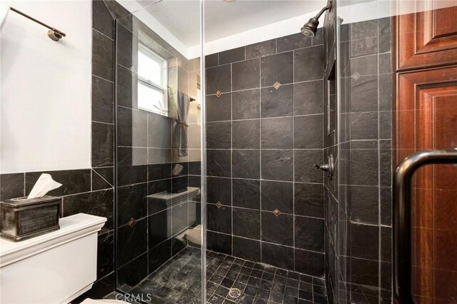 bathroom featuring tile walls, a shower with shower door, toilet, and tile patterned floors